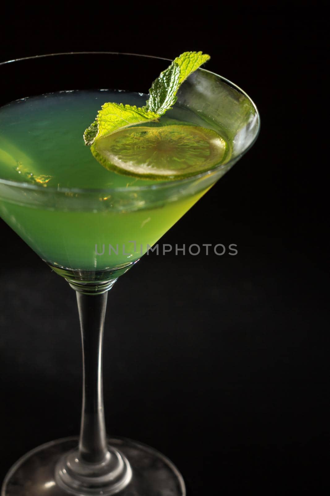 Kiwi jelly with lime pieces in the glass topped mint leaves in the black background