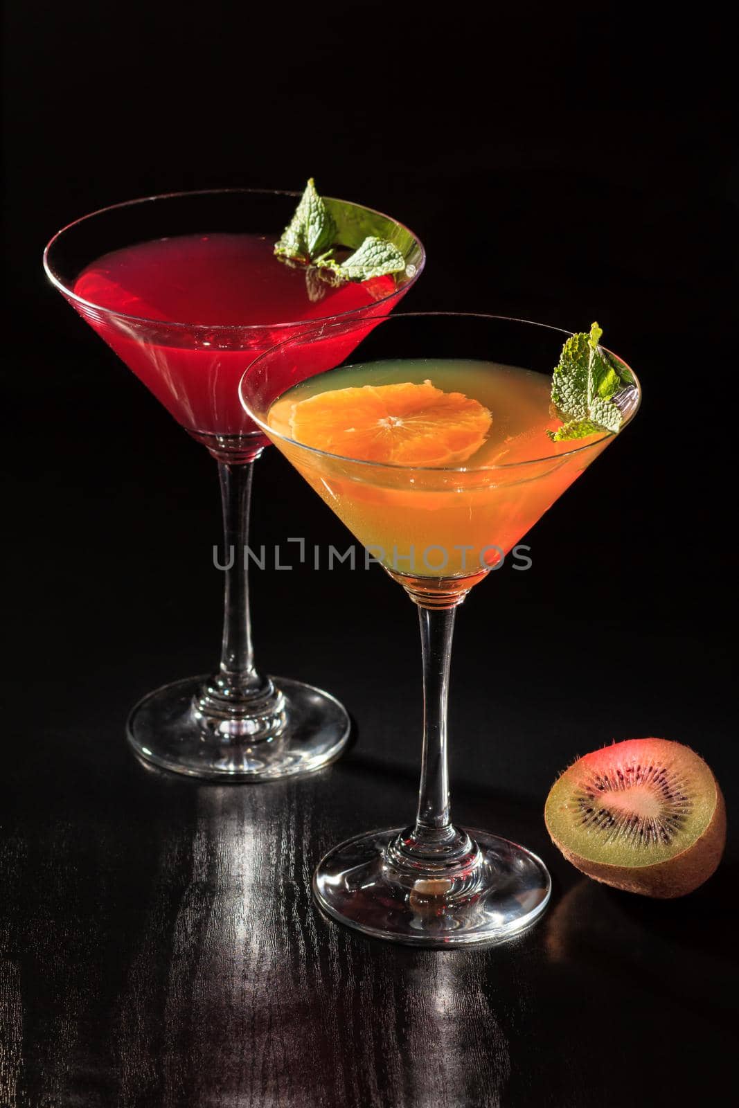 Cherry and orange jelly with lime pieces in the glasses topped mint leaves on the black background