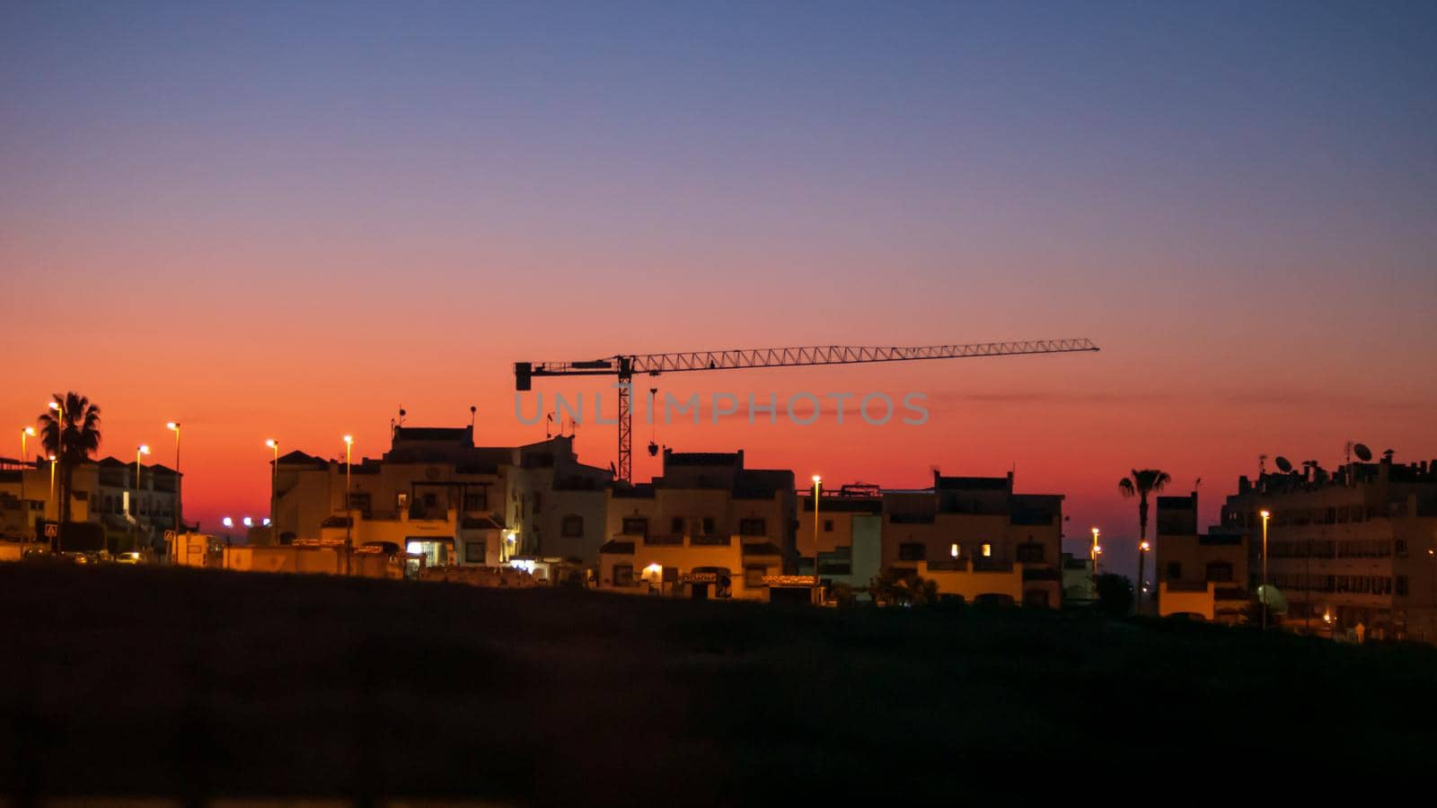 sunrise over spanish homes with crane in silhouette