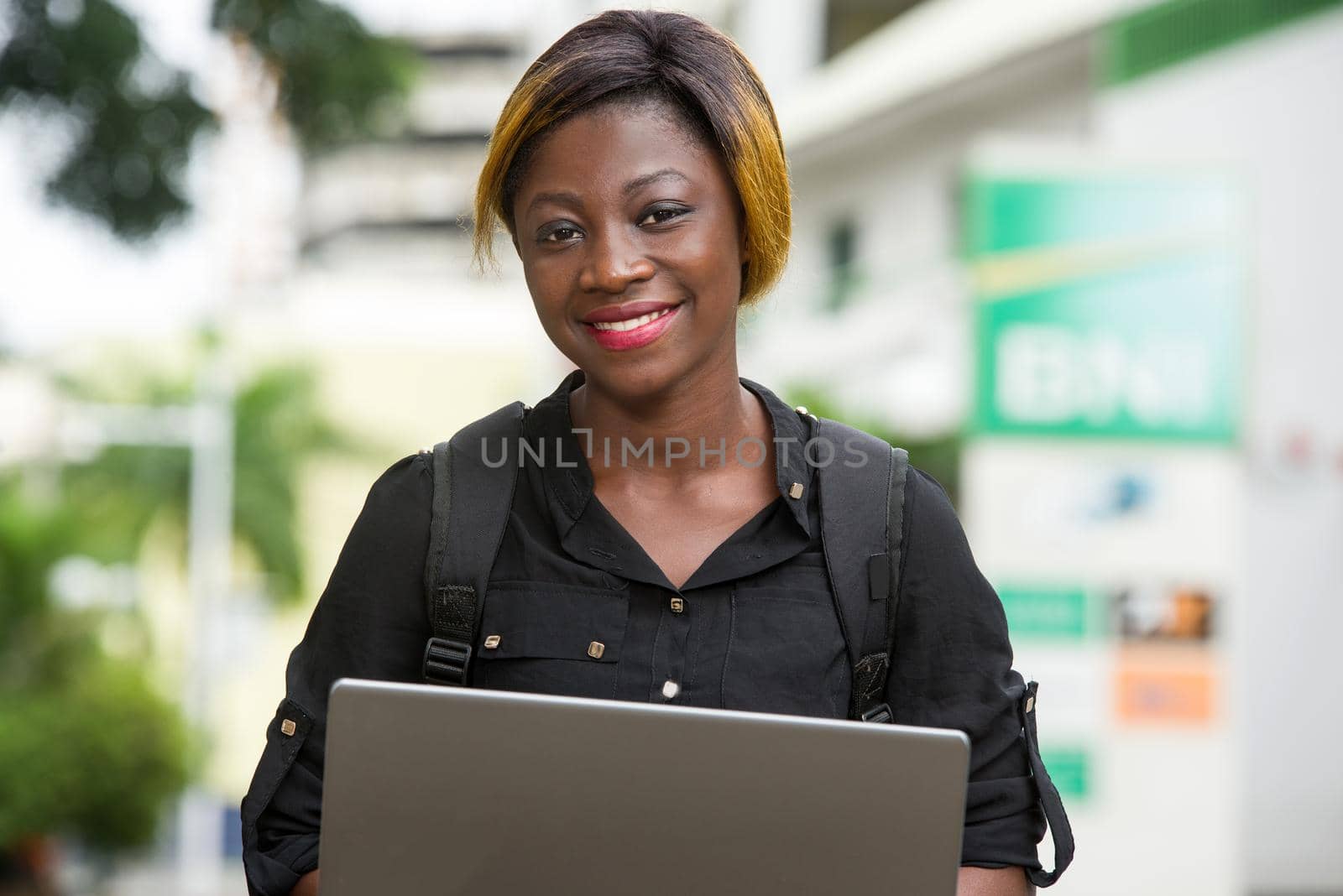 student sitting with laptop watching camera smiling.