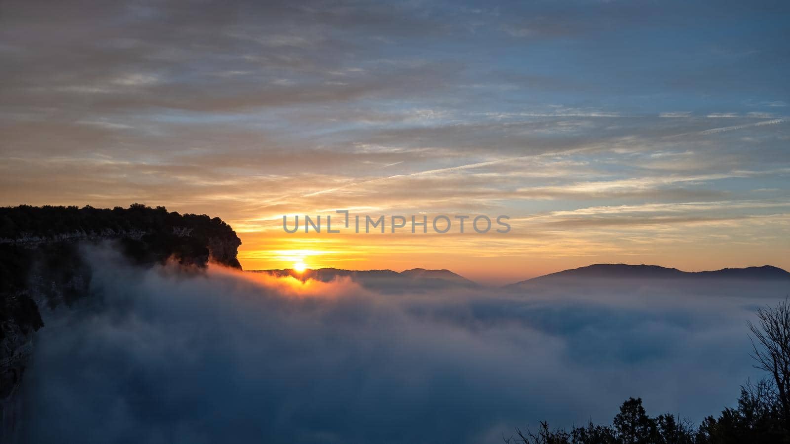 Sunrise with blue sky above the clouds in the mountains. View from high point. Very early morning with fog and colorful clouds.