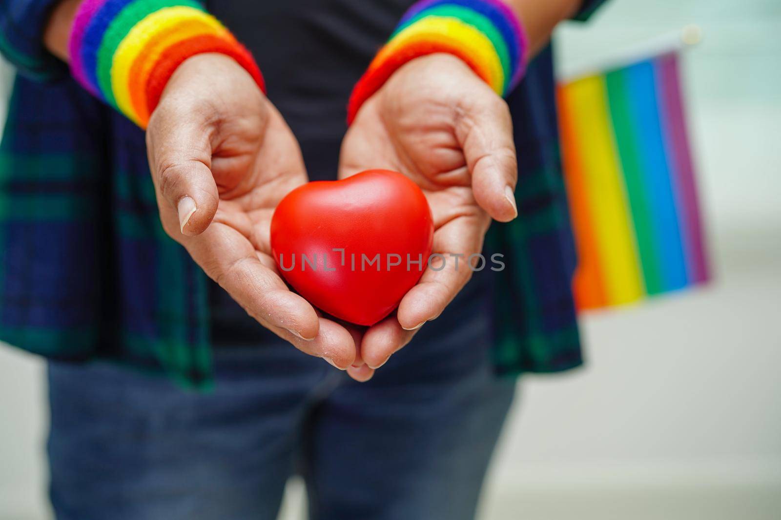 Asian woman holding red hert with rainbow flag, LGBT symbol rights and gender equality, LGBT Pride Month in June, LGBTQ, LGBTI, LGBTQA, LGBTQIA