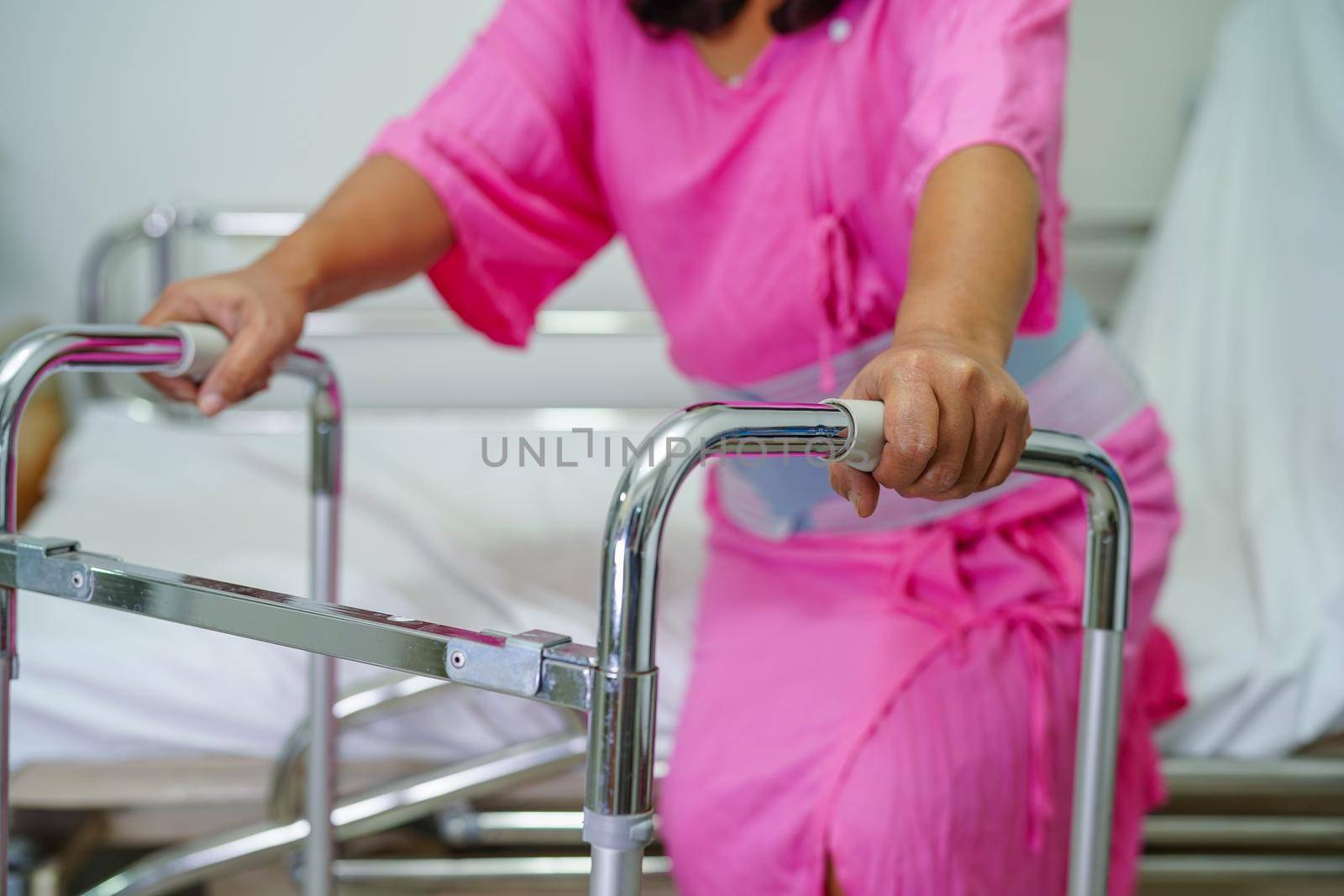 Asian middle-aged lady woman patient walk with walker at nursing hospital ward