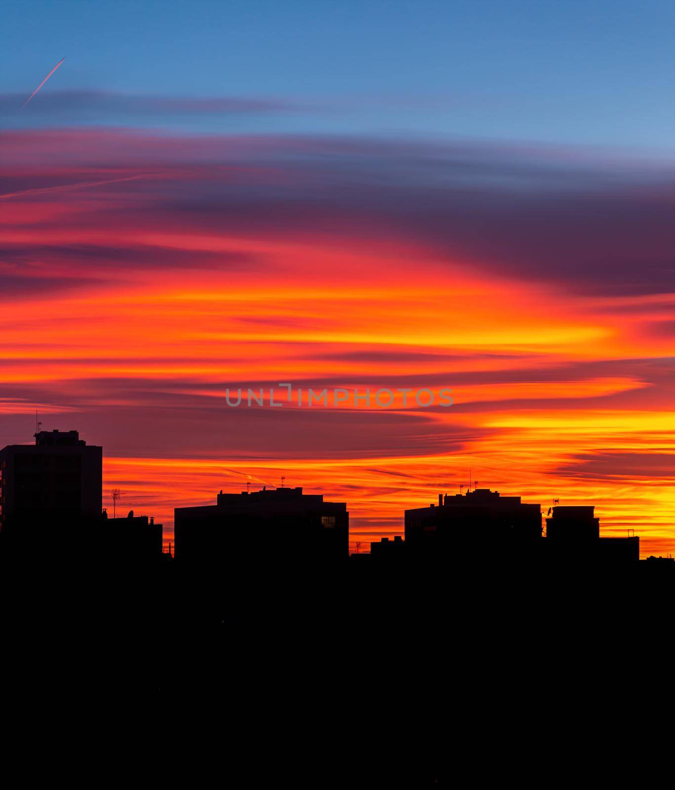 Amazing sunset with orange, pink and red stratus clouds over the city. Background for forecast and meteorology concept. Barcelona, Spain.