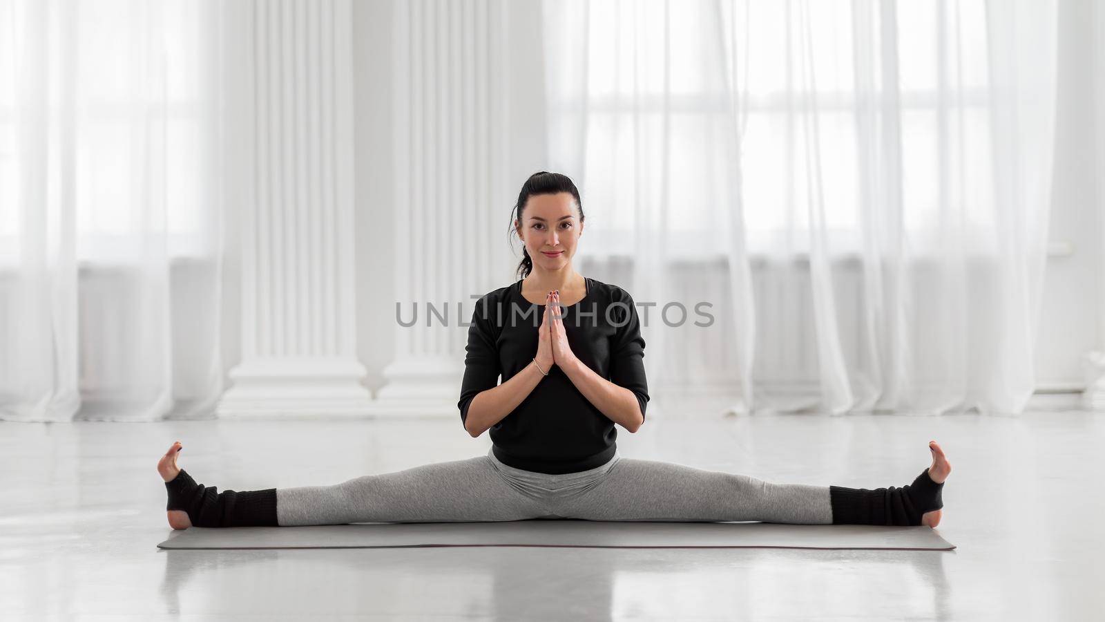Young beautiful asian woman practicing yoga pose on gray mat. Samakonasana. Straight Angle Pose. Side Splits. by apavlin