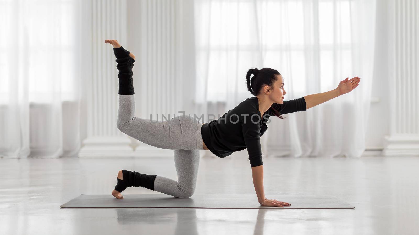 Extended Cat Cow Pose. Beautiful young asian woman practicing yoga pose on gray mat at yoga studio. by apavlin