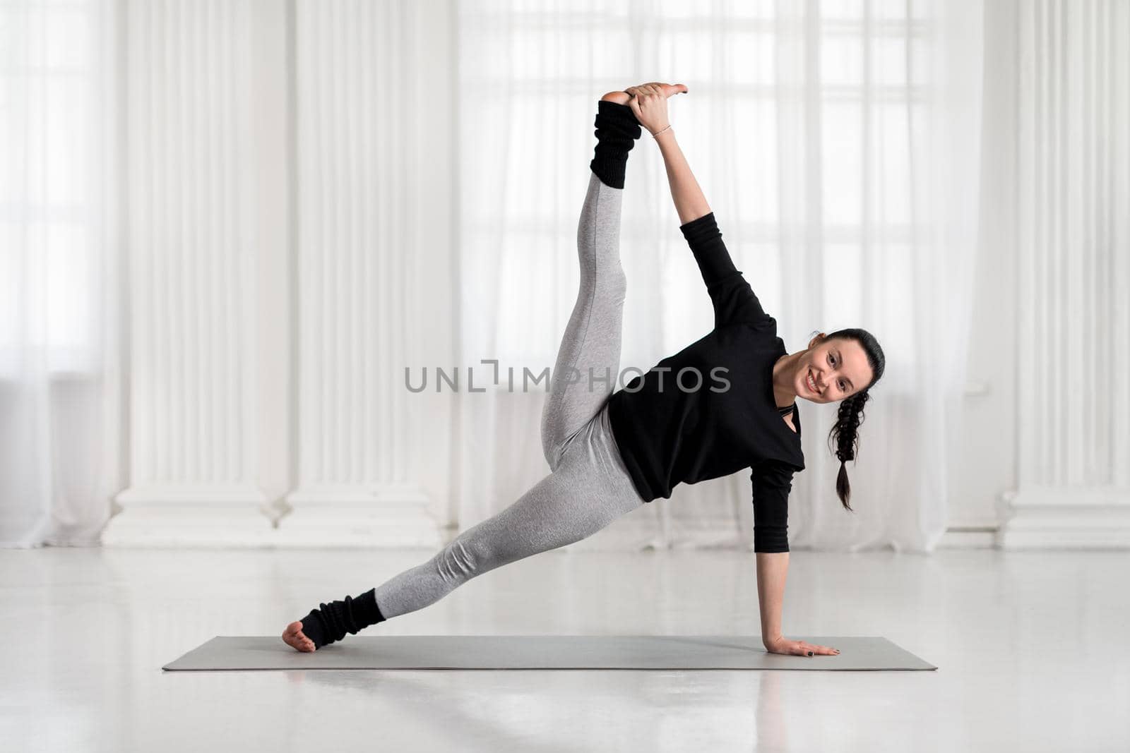 Perfect side plank. Full length of young asian woman doing side plank and looking at camera in white hall. Vasisthasana pose. Balancing asana