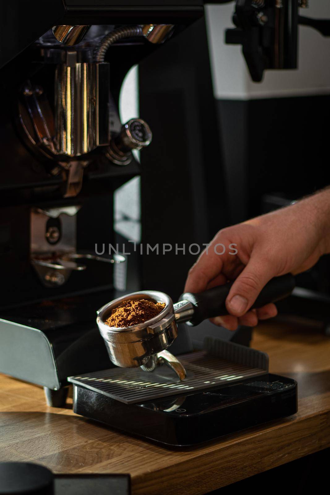 freshly ground coffee beans in a portafilter by the coffee grinder