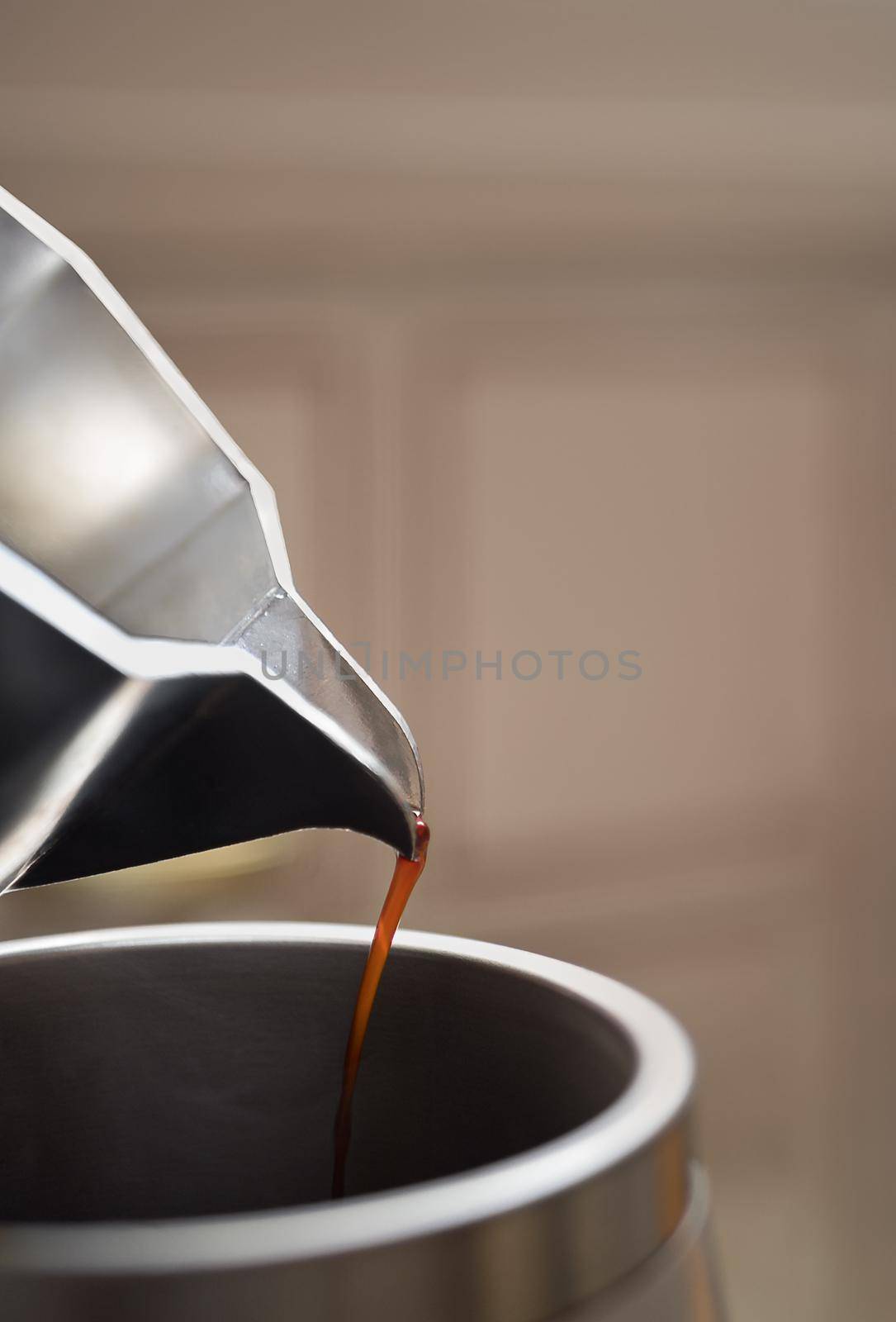 Close up of pouring out coffee from moka pot in a big metal thermo cup. Morning with espresso