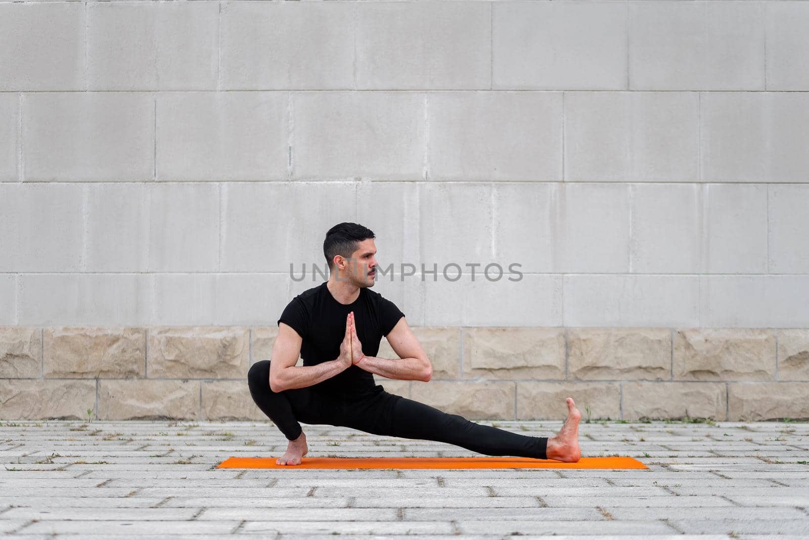 Balance and stretch exercises outdoor . Latin man practice yoga asanas in a city. by apavlin