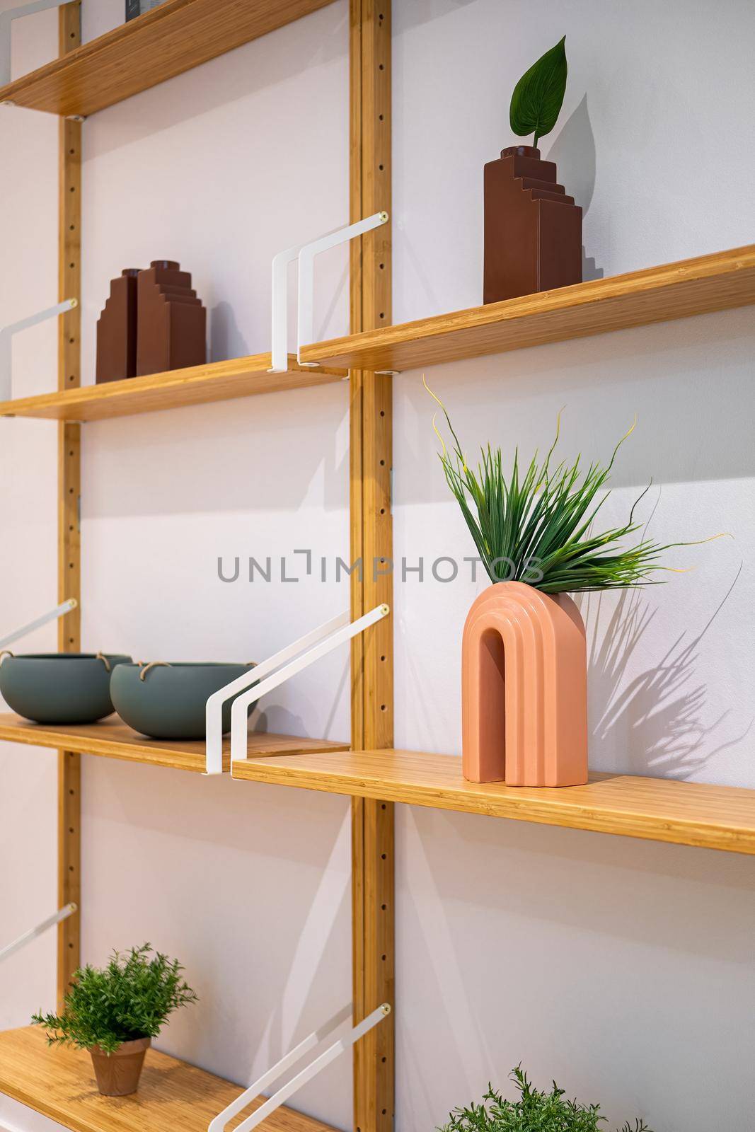 Interior wooden stand with shelves, plants, bowls and decorative elements. Home staging concept. Selective focus