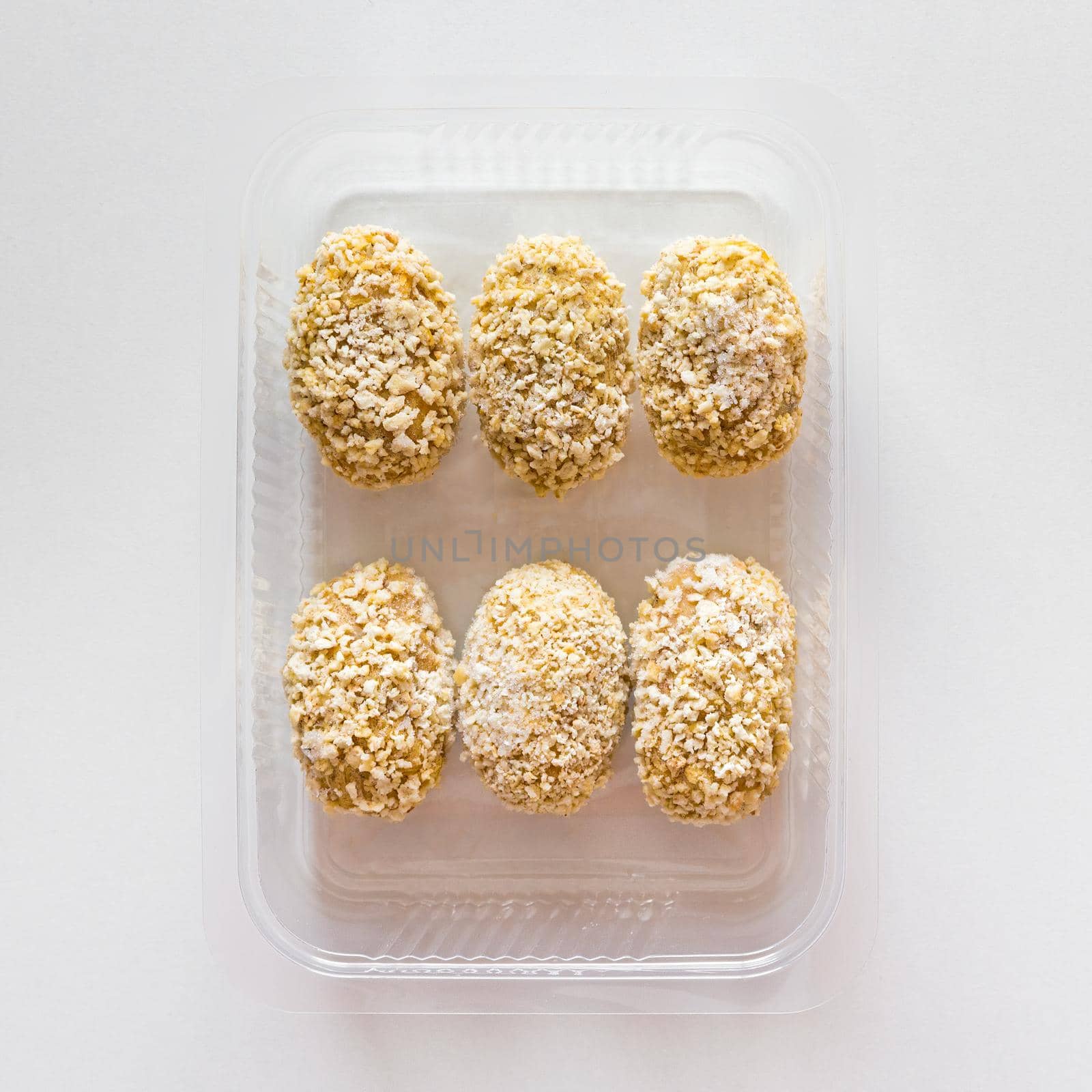 Frozen breaded croquettes in transparent tray. Mediterranean and spanish cuisine. Preserved food for sale. Top view.