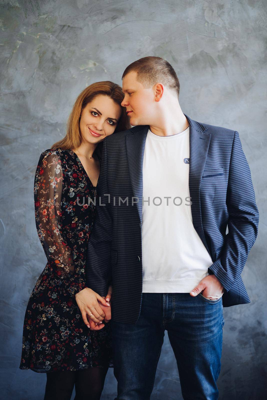 Elegant and happy couple touching each other by hands, posing at camera. by StudioLucky