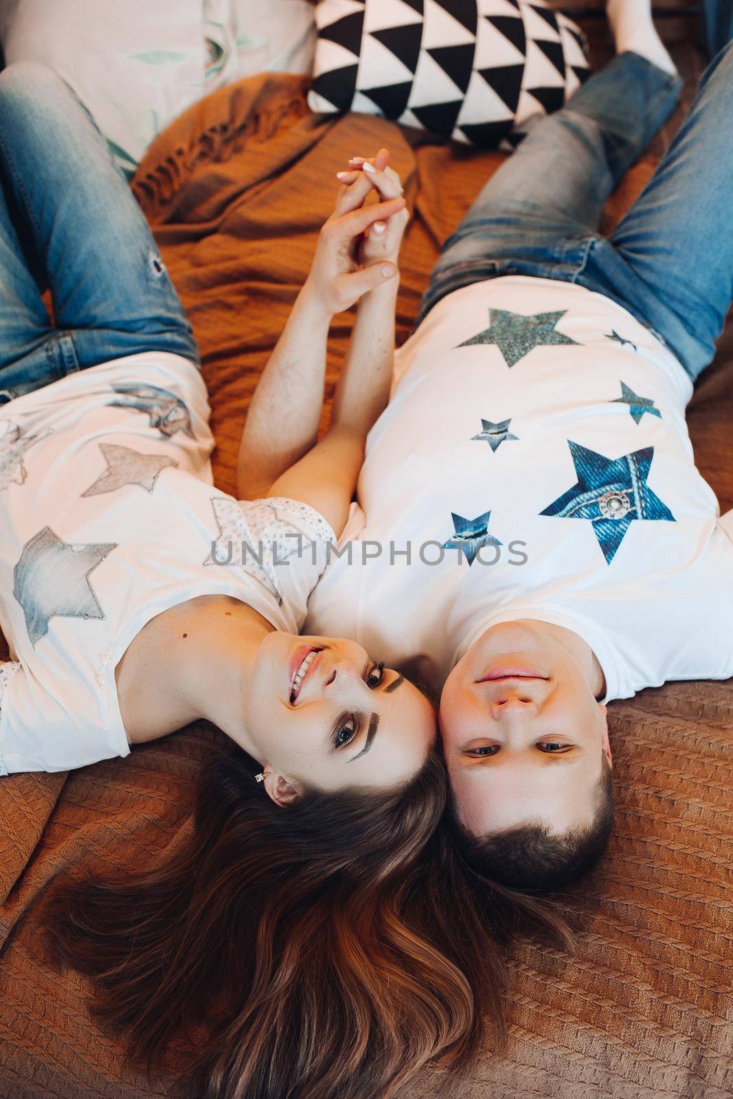 Above view of young couple laying together in bed at studio. by StudioLucky