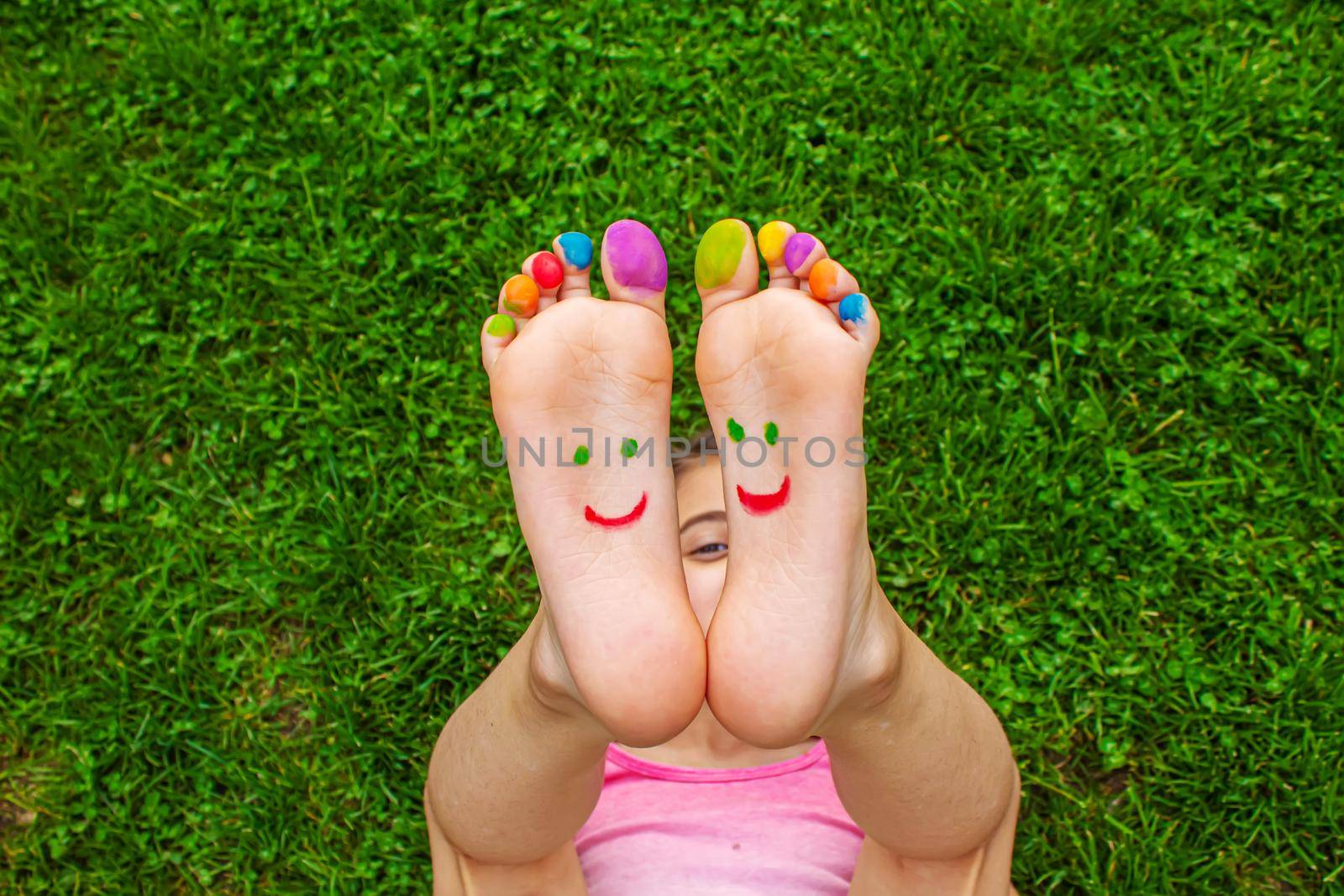 Children's feet with a pattern of paints smile on the green grass. Selective focus.child