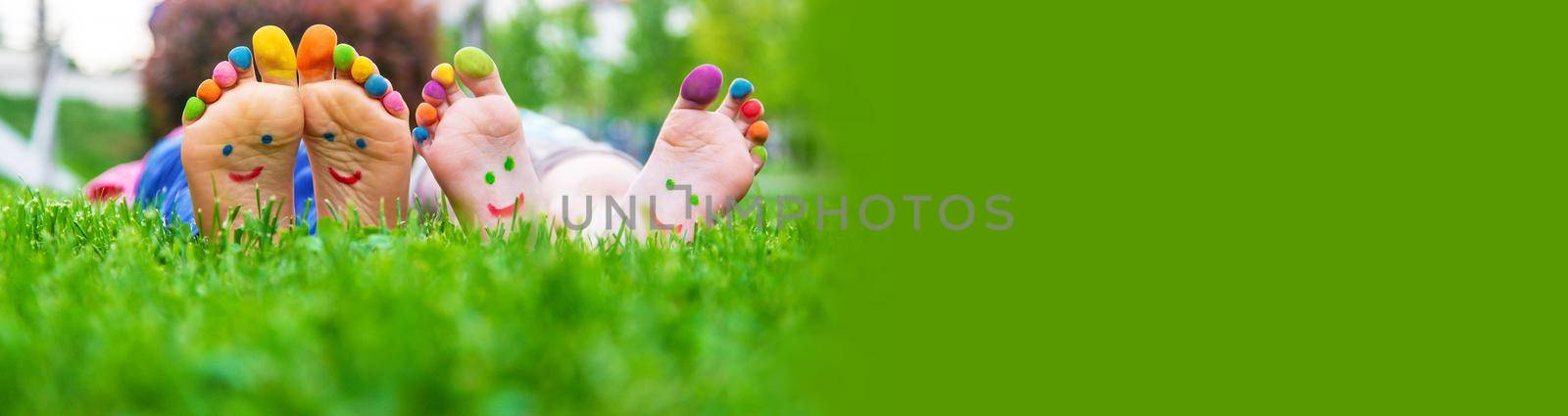 Children's feet with a pattern of paints smile on the green grass. Selective focus.child