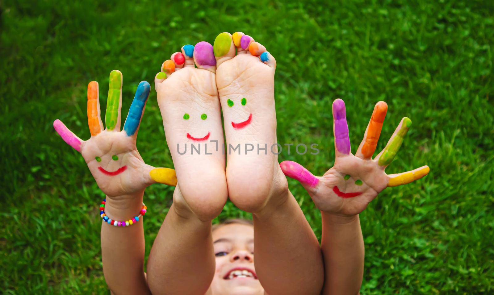 Children's feet with a pattern of paints smile on the green grass. Selective focus.child