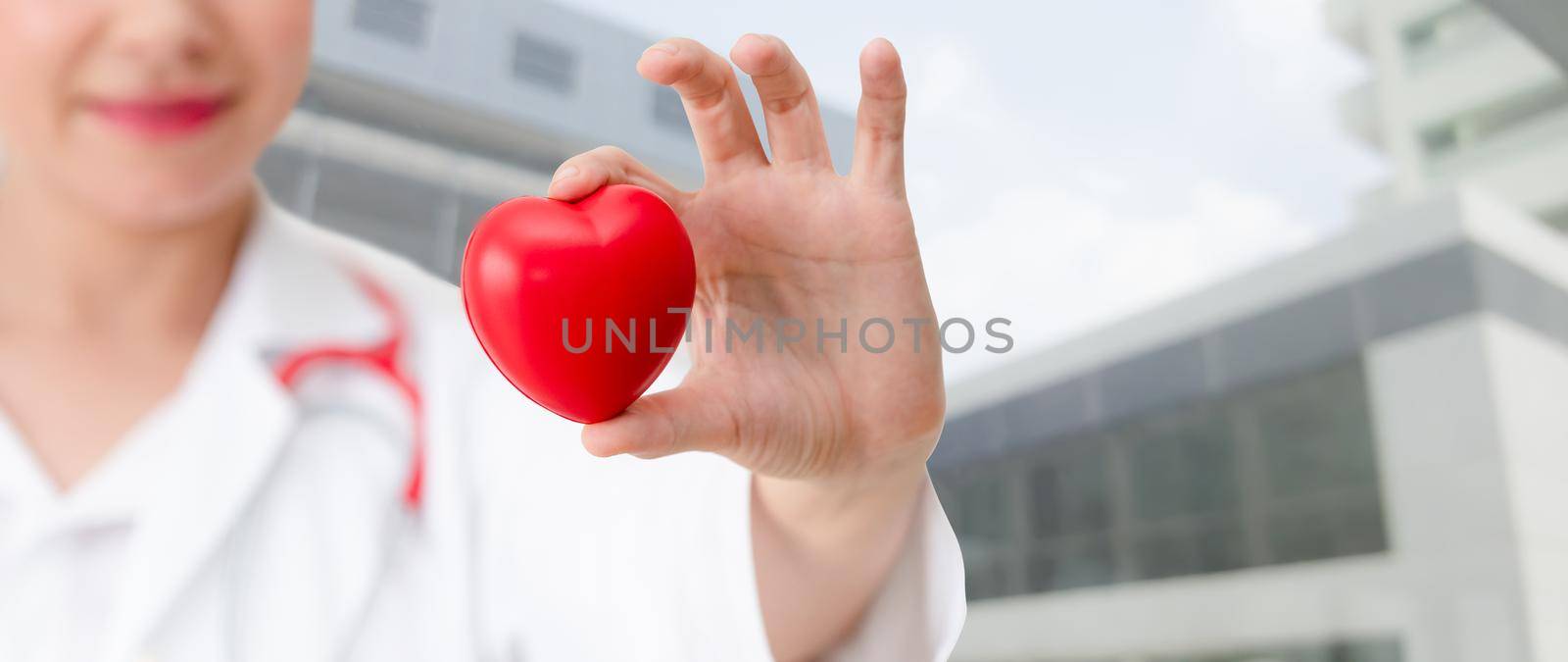 Doctor holding a red heart at hospital office. by biancoblue