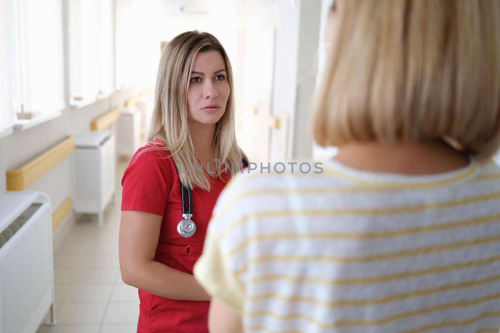 Woman doctor communicates with patient in corridor of hospital by kuprevich