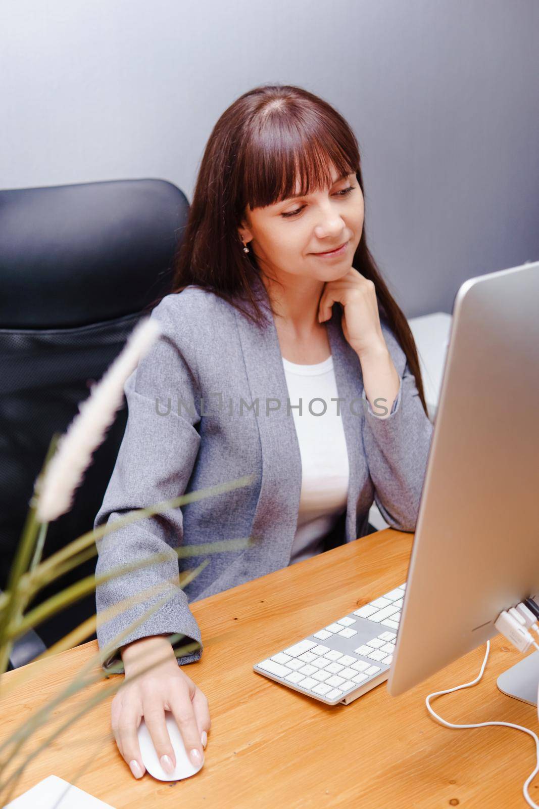 A brunette woman at a computer in the workplace. Business concept.