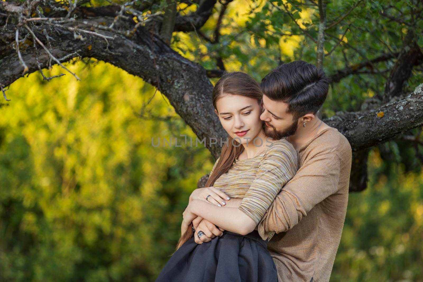 young couple hugging near a tree