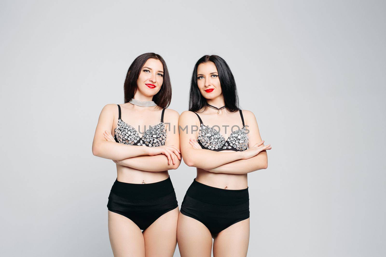 Seductive twins in shine and glamorous lingerie posing with crossed hands. by StudioLucky