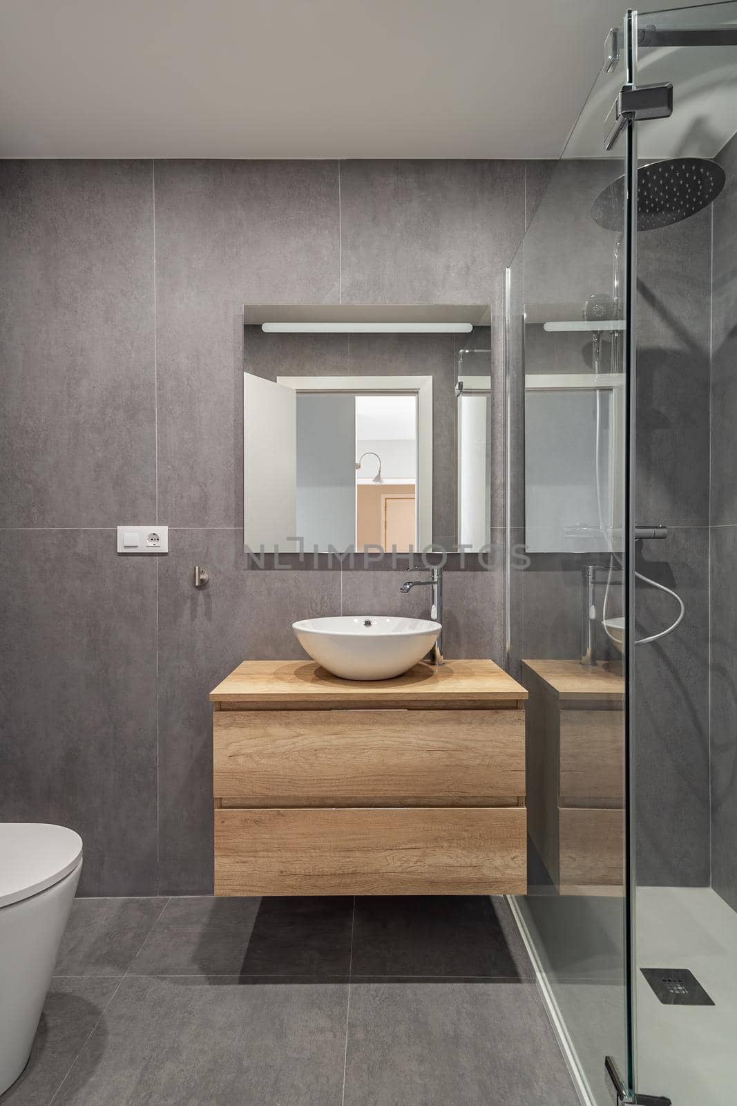 Modern refurbished bathroom in minimalistic style with sink mirror and shower cabin.