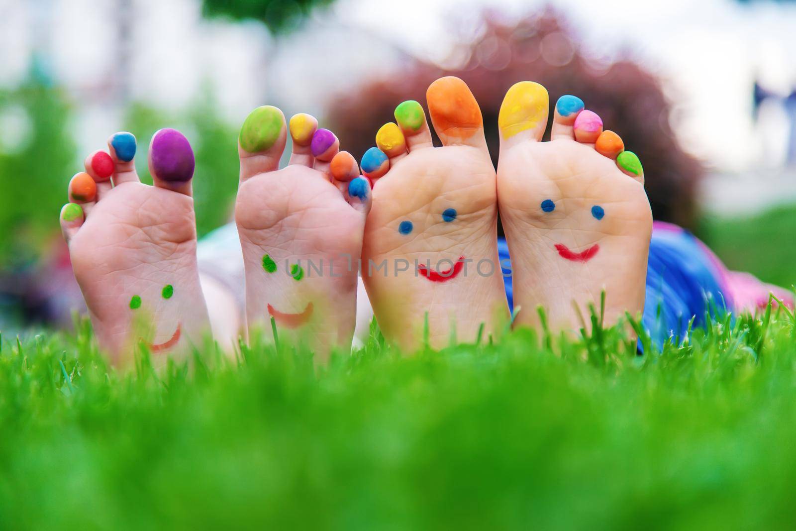 Children's feet with a pattern of paints smile on the green grass. Selective focus.child