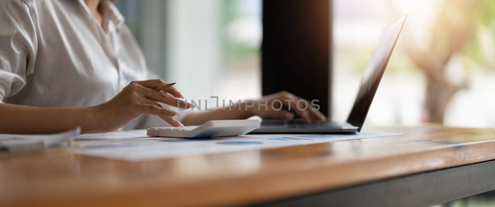 Close up business accountant woman using calculator and laptop computer for calculate about finance accounting. finance accounting concept by nateemee
