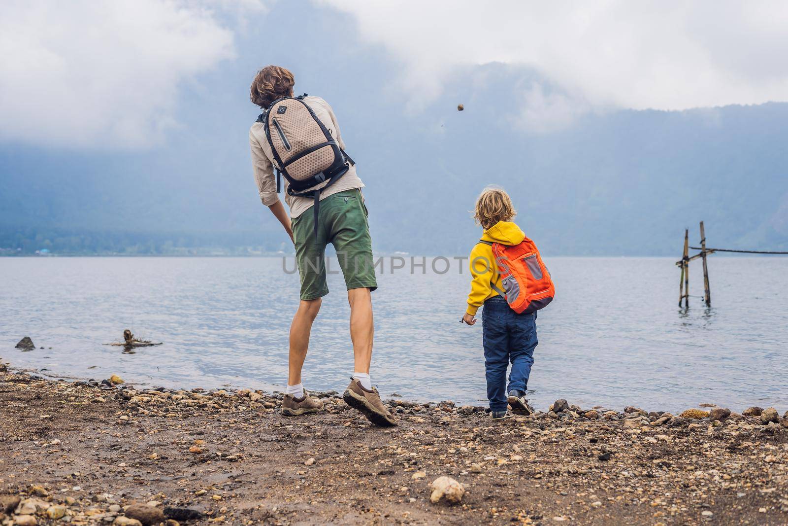 Father and son at the lake Bratan and the mountains covered with clouds by galitskaya
