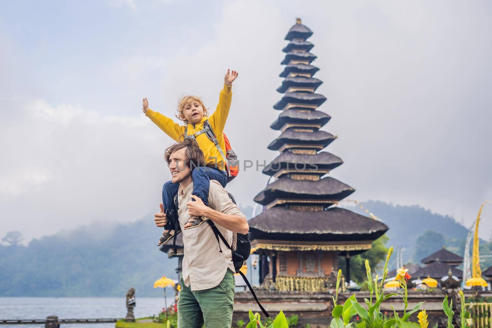 Dad and son in the background of Pura Ulun Danu Bratan, Bali. Hindu temple surrounded by flowers on Bratan lake, Bali. Major Shivaite water temple in Bali, Indonesia. Hindu temple. Traveling with children concept by galitskaya