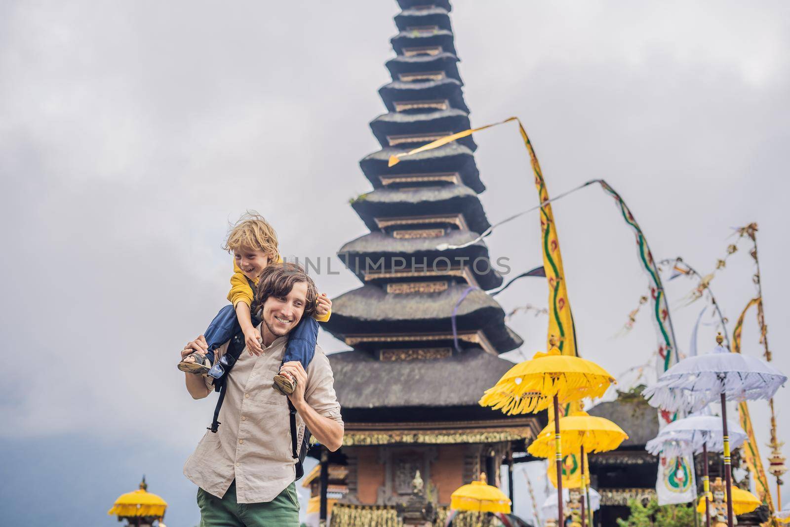 Dad and son in the background of Pura Ulun Danu Bratan, Bali. Hindu temple surrounded by flowers on Bratan lake, Bali. Major Shivaite water temple in Bali, Indonesia. Hindu temple. Traveling with children concept by galitskaya