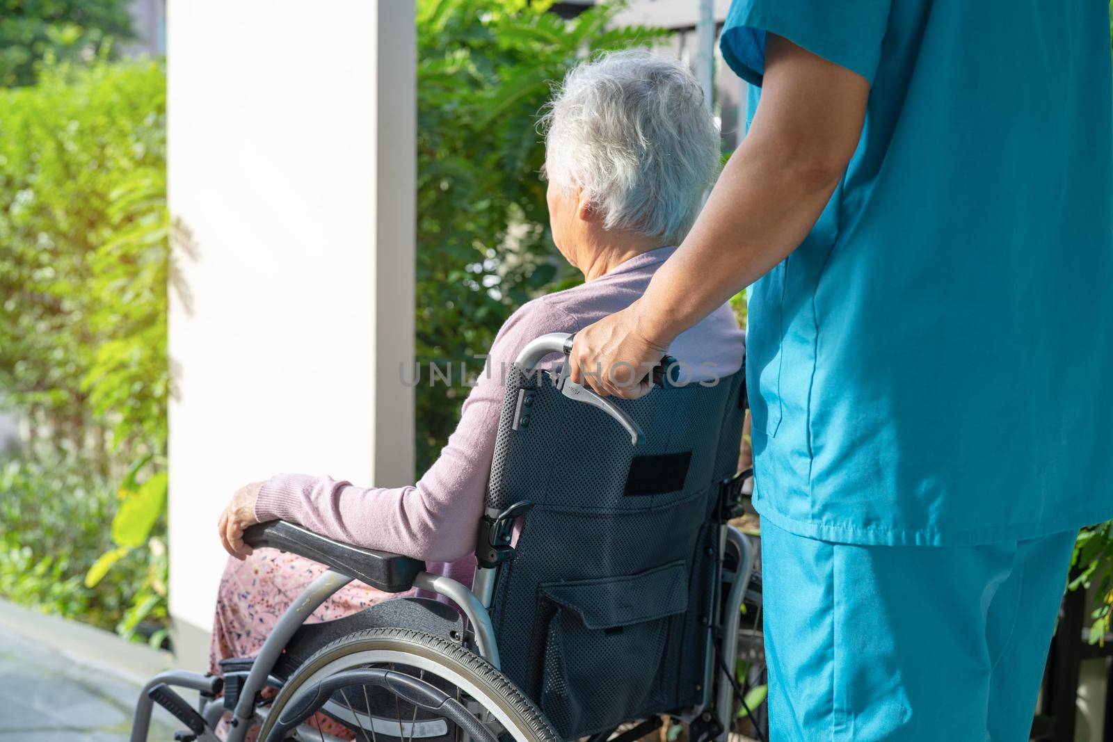 Caregiver help and care Asian senior or elderly old lady woman patient sitting in wheelchair on ramp at nursing hospital, healthy strong medical concept by pamai