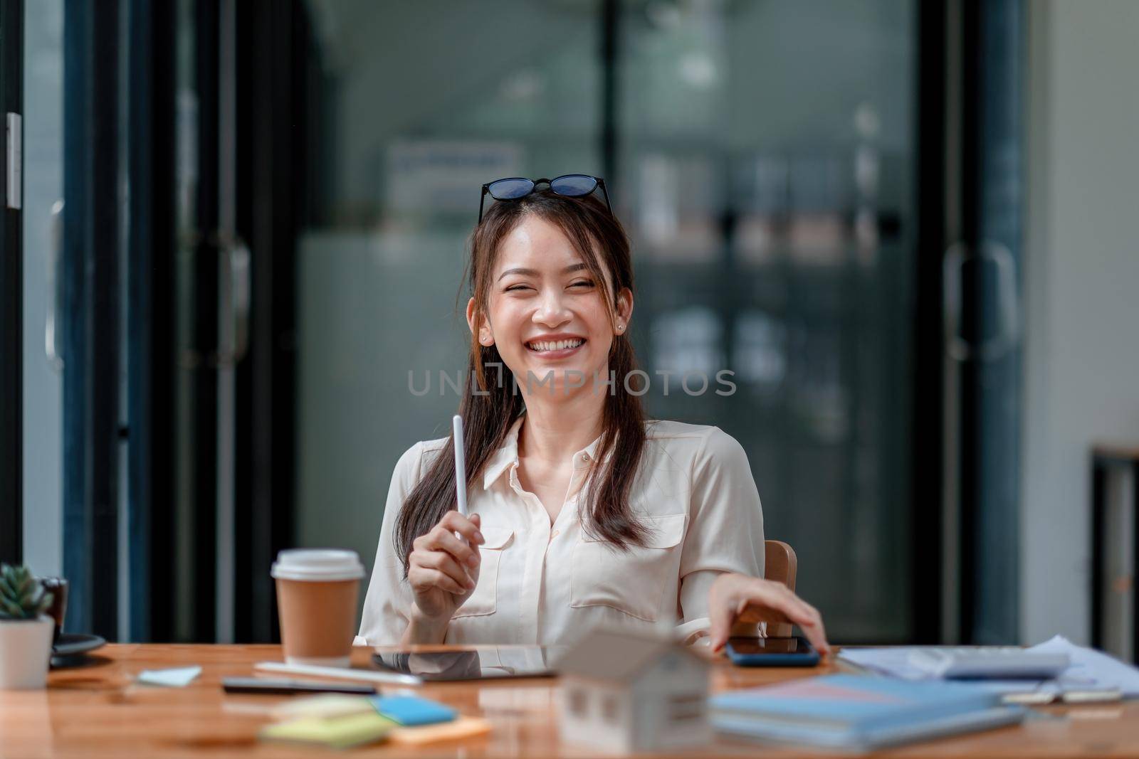 Portrait of happy young asian girl working at a coffee shop with a digital tablet and pen stylus. Real estate concept.