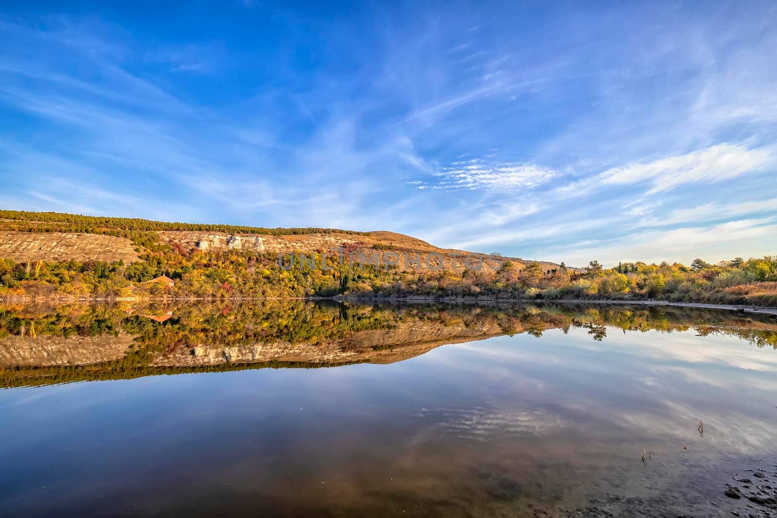 Fall foliage colors reflected in still lake water on a beautiful autumn day 