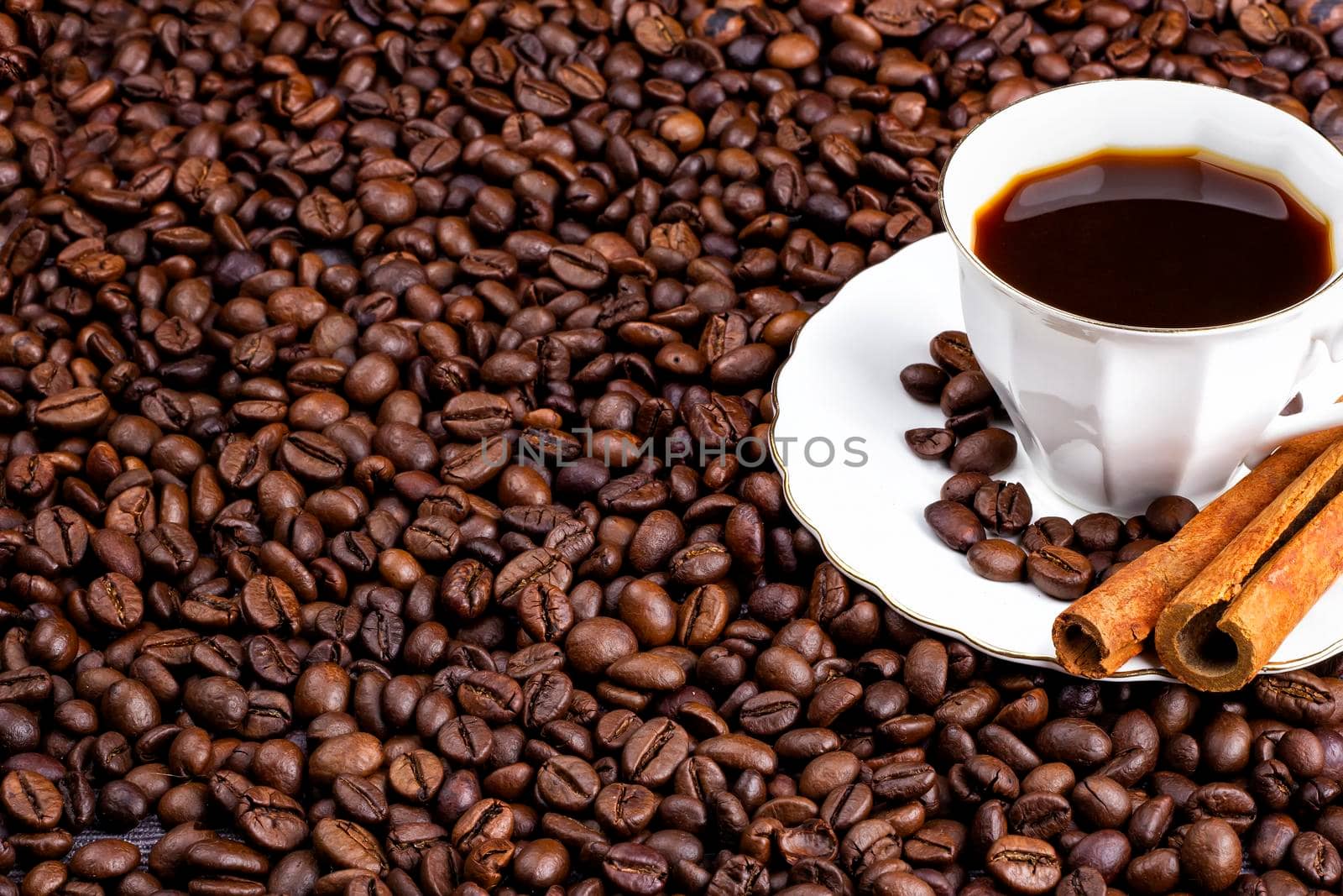 Coffee beans and a cup of coffee with cinnamon. Horizontal view