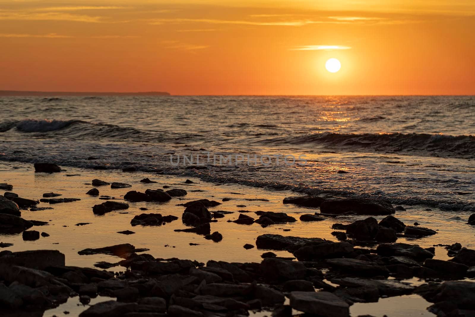 Stunning morning seascape with sun and stones on the water