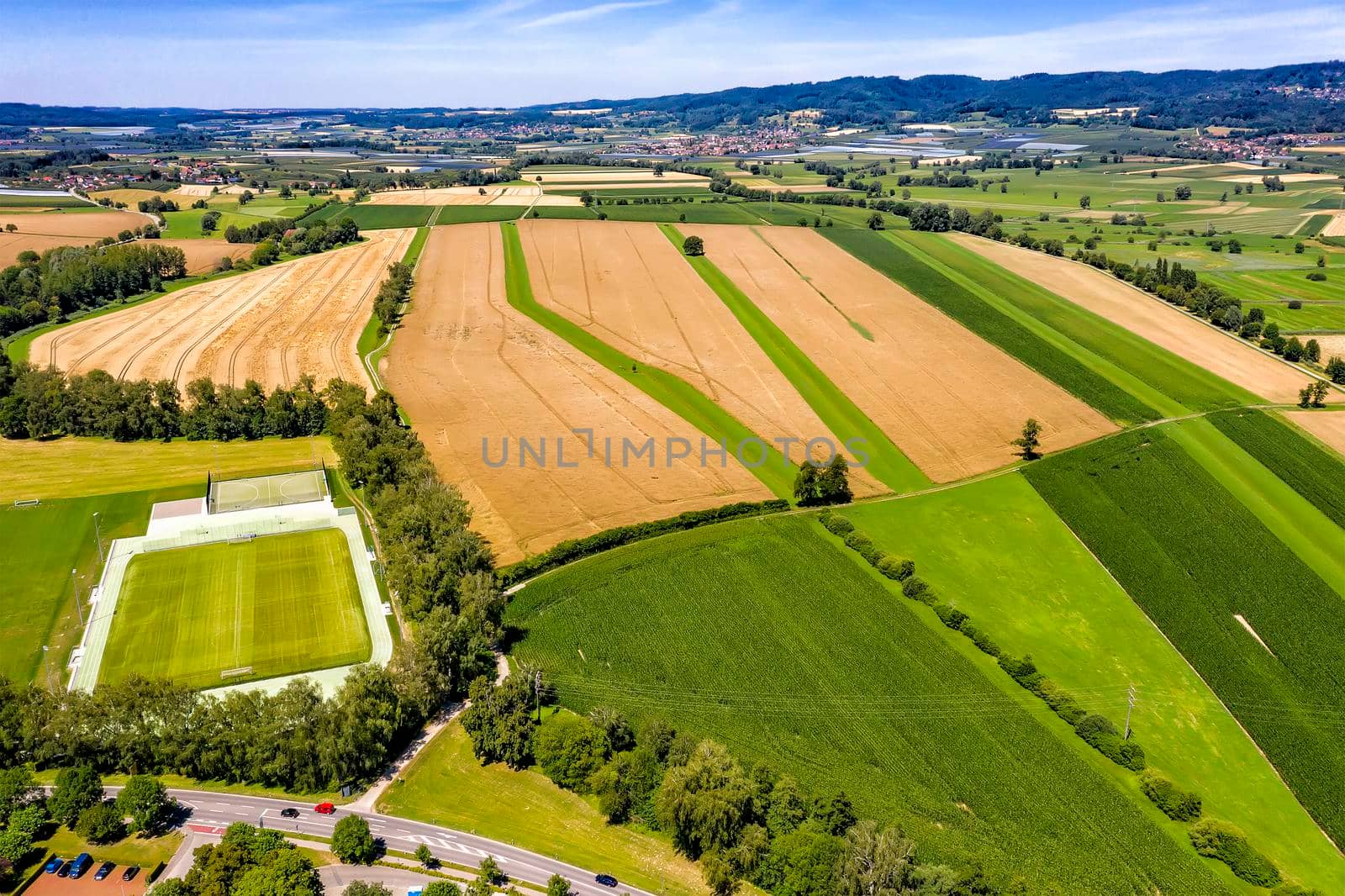 Aerial view from drone of the countryside with a football field and beautifully cultivated fields in Germany