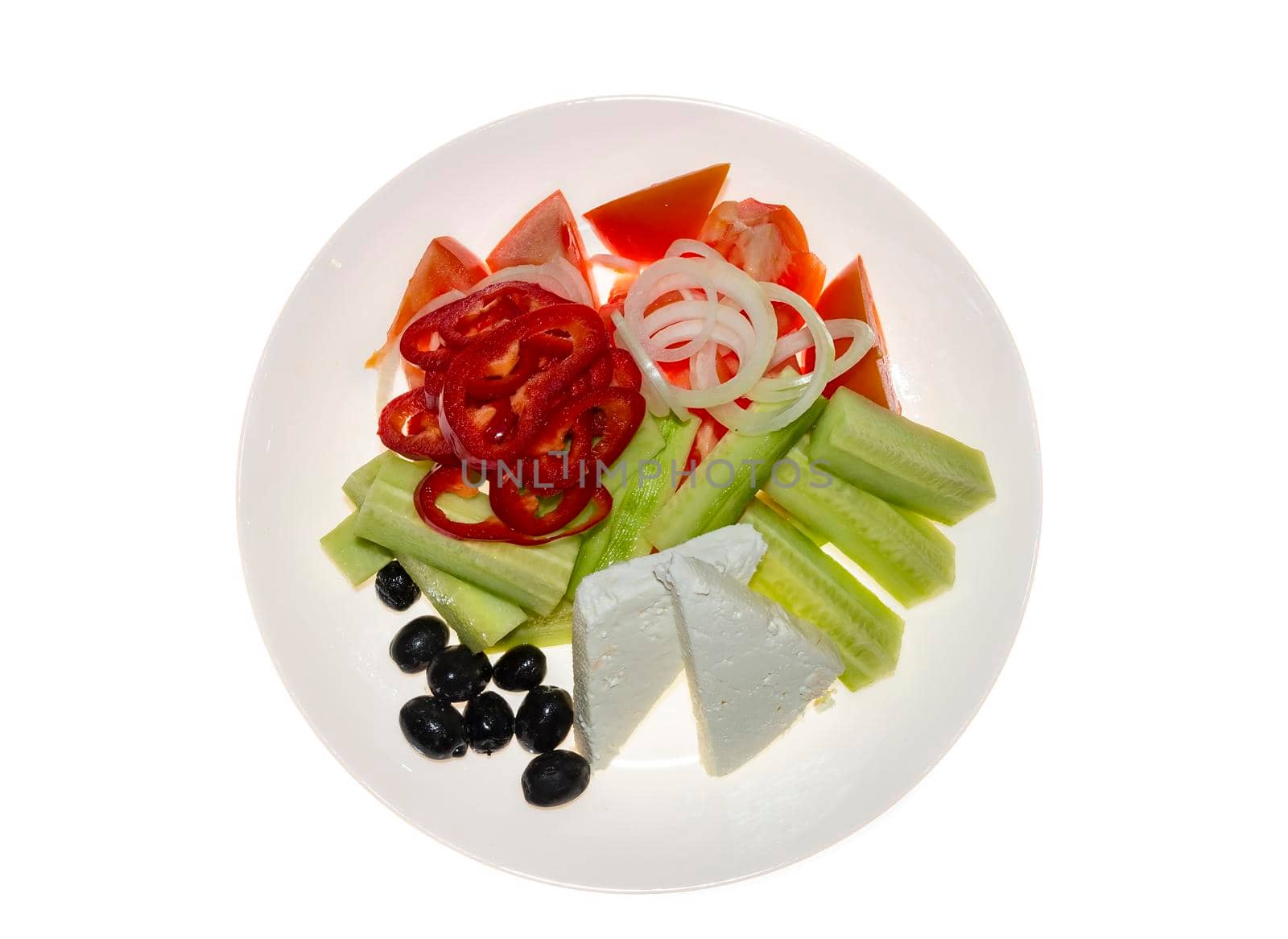 Traditional Greek salad. Tomatoes, sliced cucumbers, paprika, onion, black olives, cheese in ceramic plate, isolated on white background. Top view