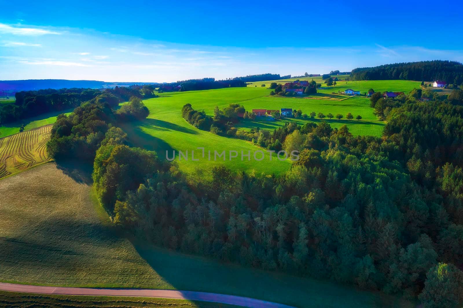 Amazing spring landscape with green rolling hills and farmhouses in the heart of Germany, before sunset