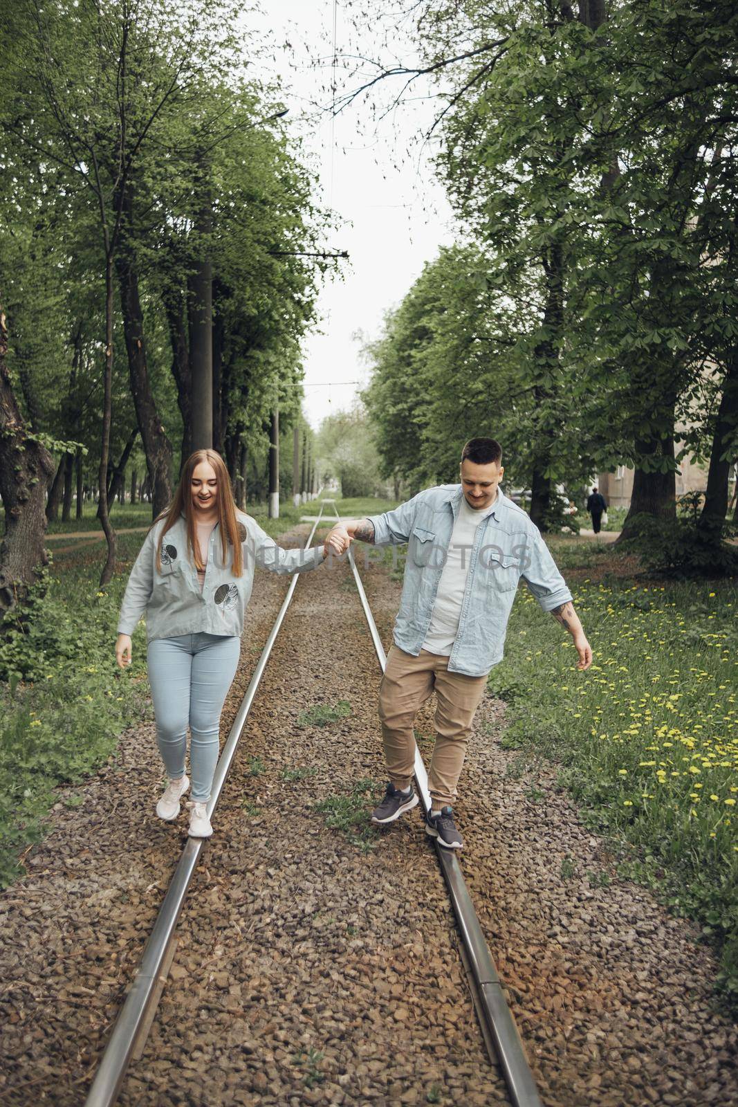 a couple in love walks fooling around on tram tracks by Symonenko