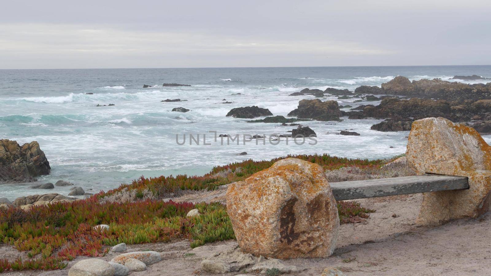 Rocky craggy ocean coast, sea waves, Monterey California. Wooden empty bench. by DogoraSun