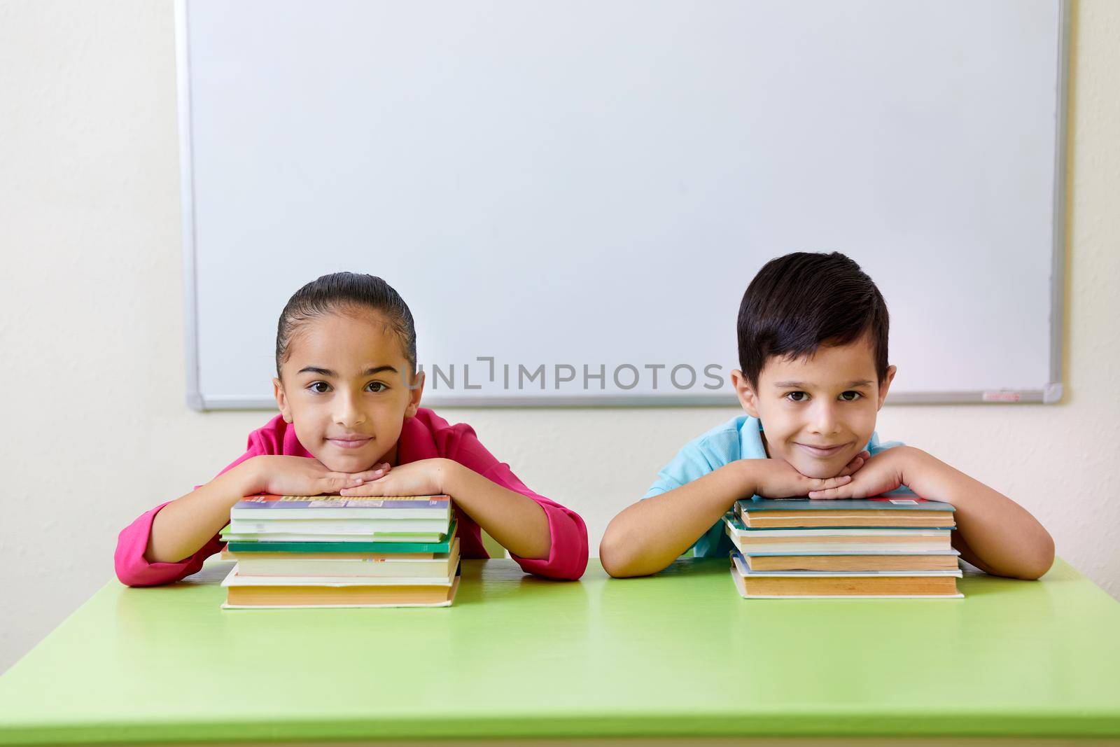 Preschool children playing with books sitting at a table by Mariakray