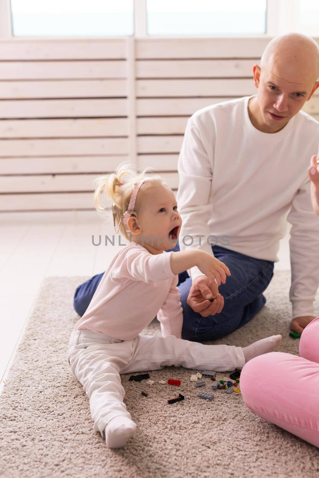 Happy child girl with cochlear implant having fun with her father - hearing aid for deaf and innovative health technology