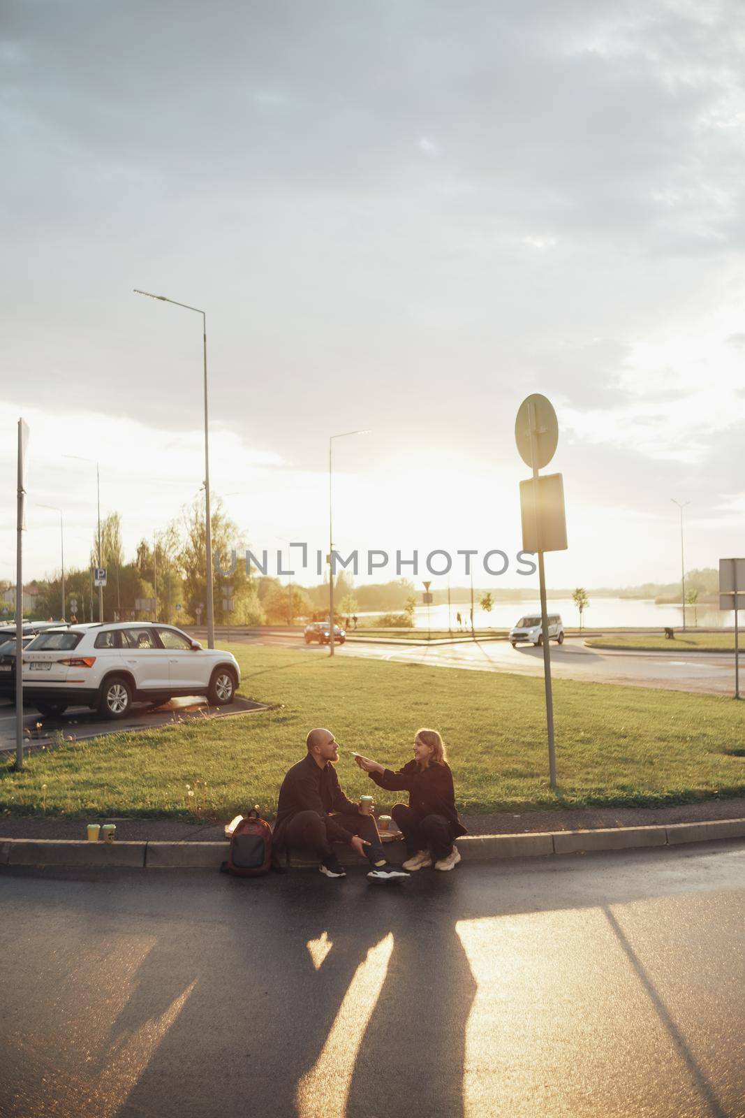 lovers eat pizza sitting on the lawn during sunset by Symonenko