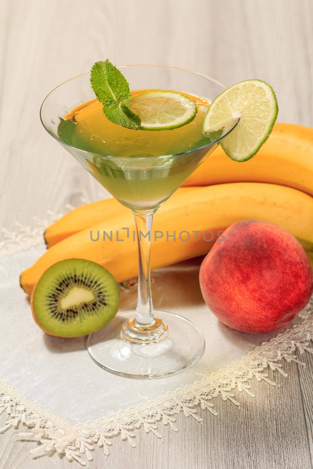 Kiwi jelly with lime pieces in the glass topped mint leaves, nectarine, kiwi and banana on the white napkin