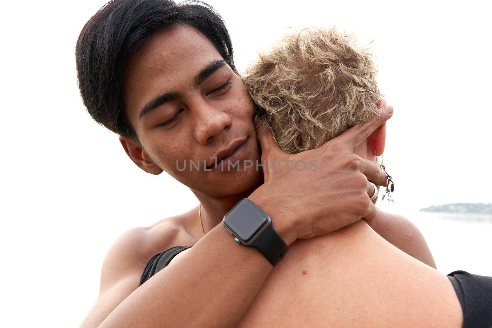 Young asian man hugging a adult caucasian woman next to the sea by WesternExoticStockers