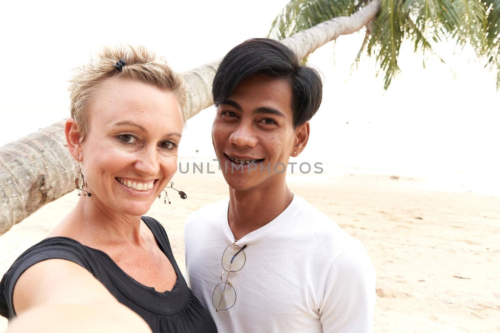 Adult caucasian woman taking a selfie with her asian couple in a beach by WesternExoticStockers