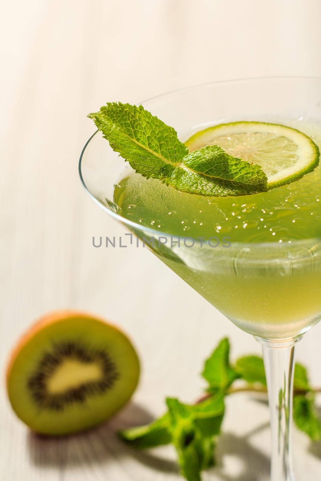 Kiwi jelly with lime pieces in the glass topped mint leaves Close up selective focus