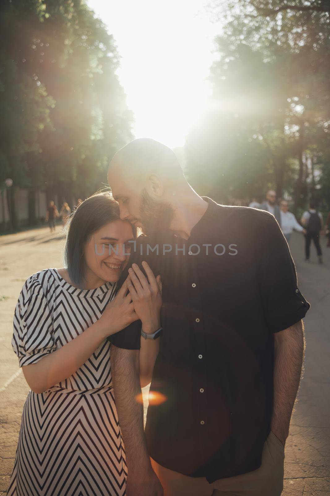 lovers take a walk in the park in the summer. the girl firmly holds the guy's hand. glare of the sun by Symonenko